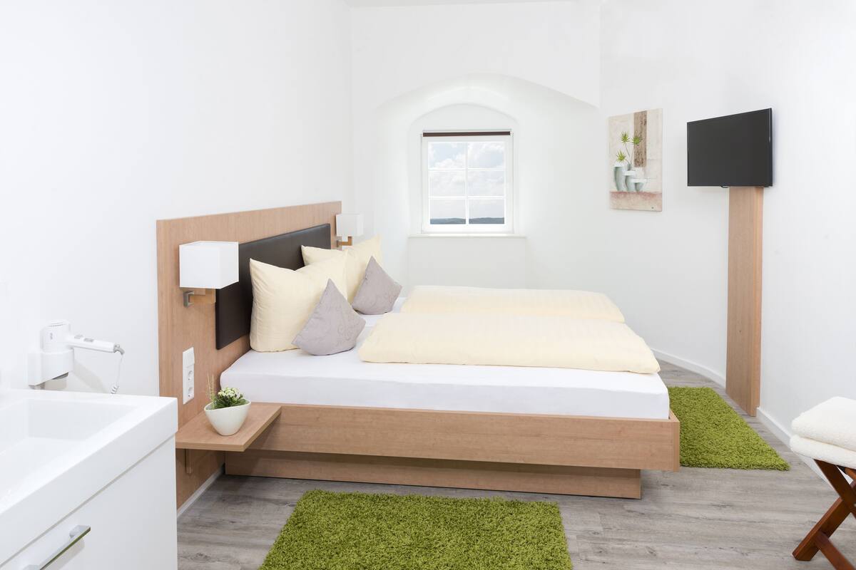 A modern bedroom with a bed, bedside table, and a window.