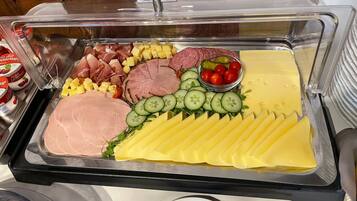 A buffet with various food items including meats, cheeses, and vegetables.