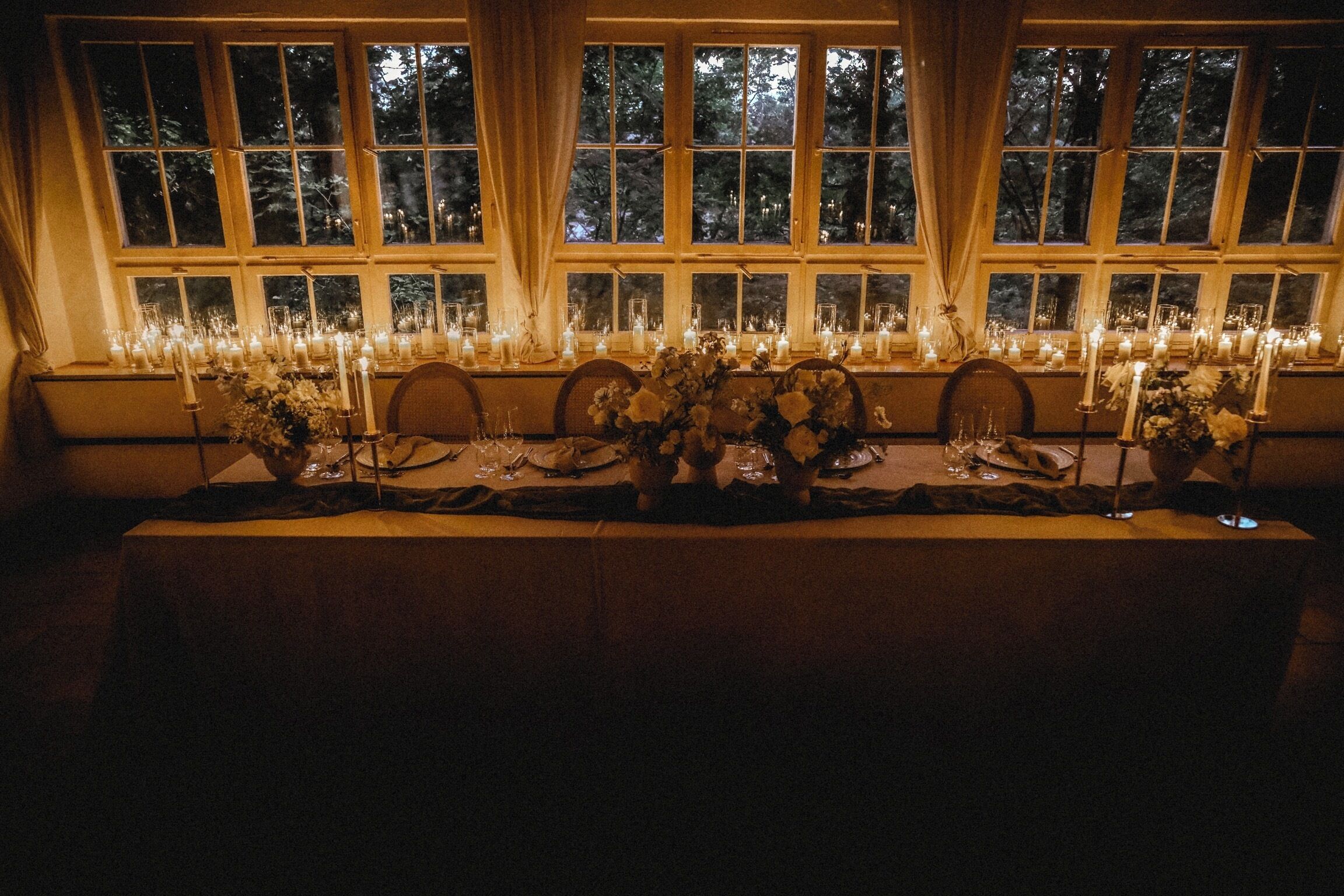 A long table set for a formal event with candles and floral arrangements.