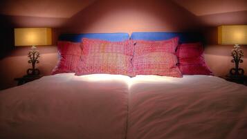 Een tweepersoonsbed met een blauw hoofdbord en twee bedlampjes.