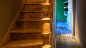 A wooden staircase with a handrail, leading to a room with a green wall and a tiled floor. - Menin Gate House  1 (Ypres)