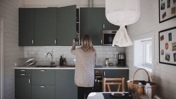 Ett modernt kök med mörkgröna skåp, en vit bänkskiva och en matplats med ett bord dukat för två personer.
