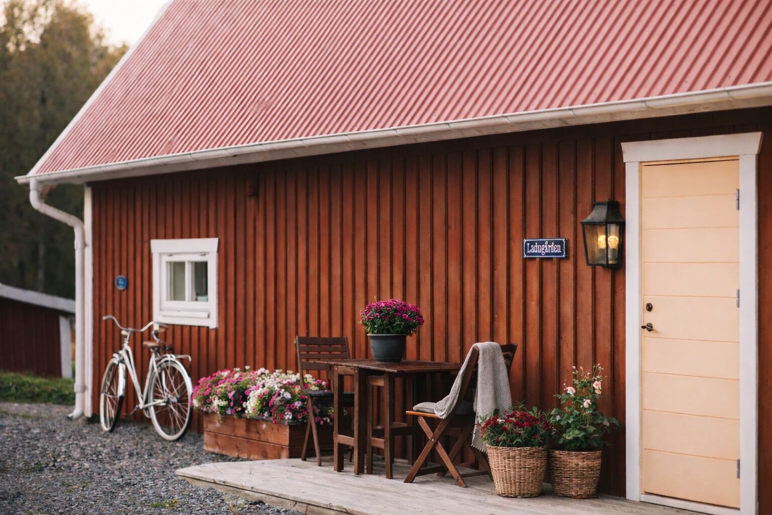 A wooden building with a corrugated metal roof, a sign reading "Ladengarden," and a table with chairs and potted plants outside.