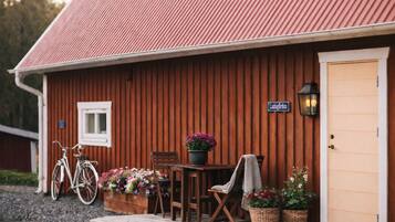 A wooden building with a corrugated metal roof, a sign reading "Ladengarden," and a table with chairs and potted plants outside.
