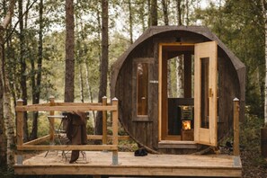 Una cabaña rústica de madera con una puerta grande, un porche pequeño y una chimenea en su interior.