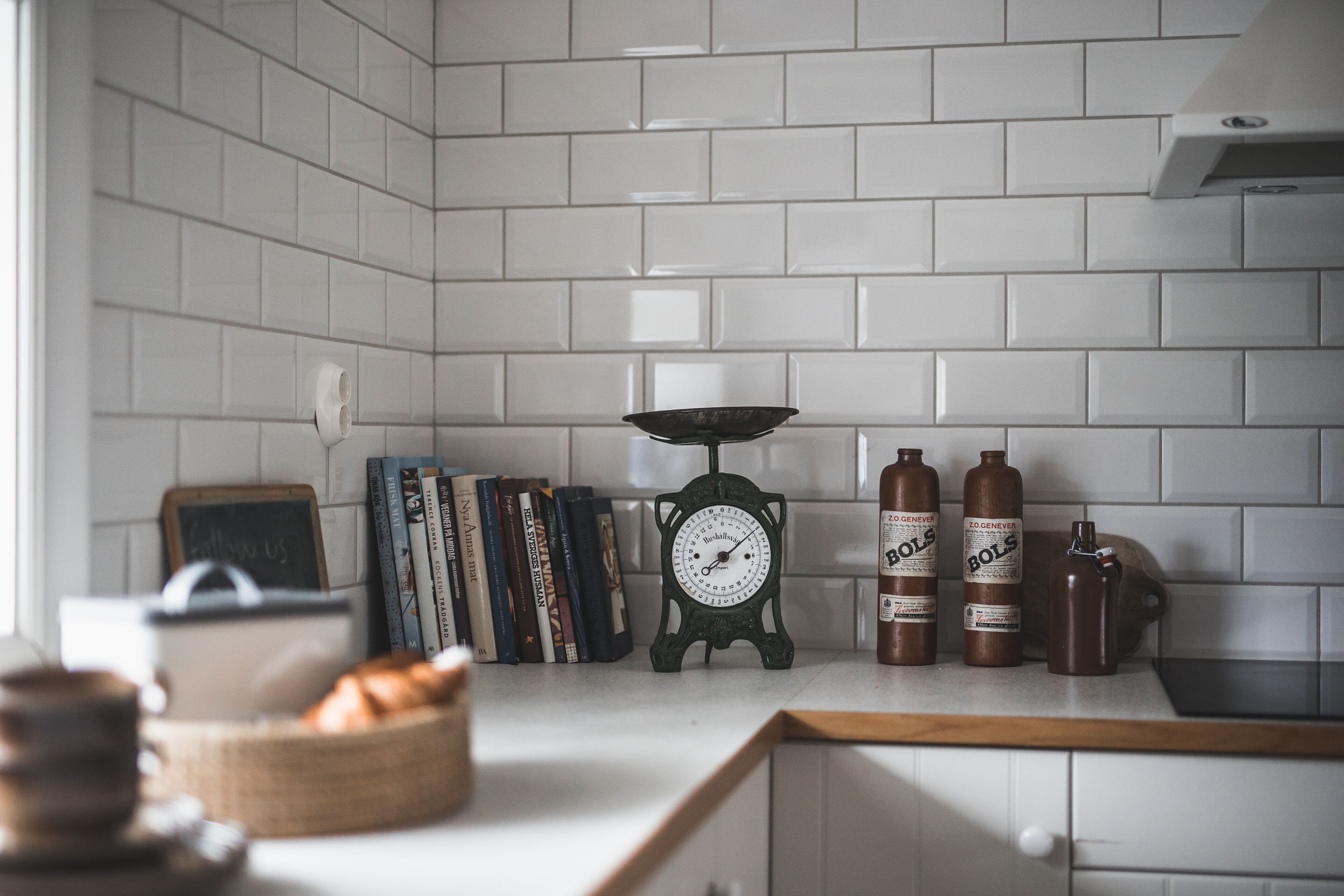 Een keuken met witte tegels, een weegschaal en flessen met de tekst 'ZOGENER'.