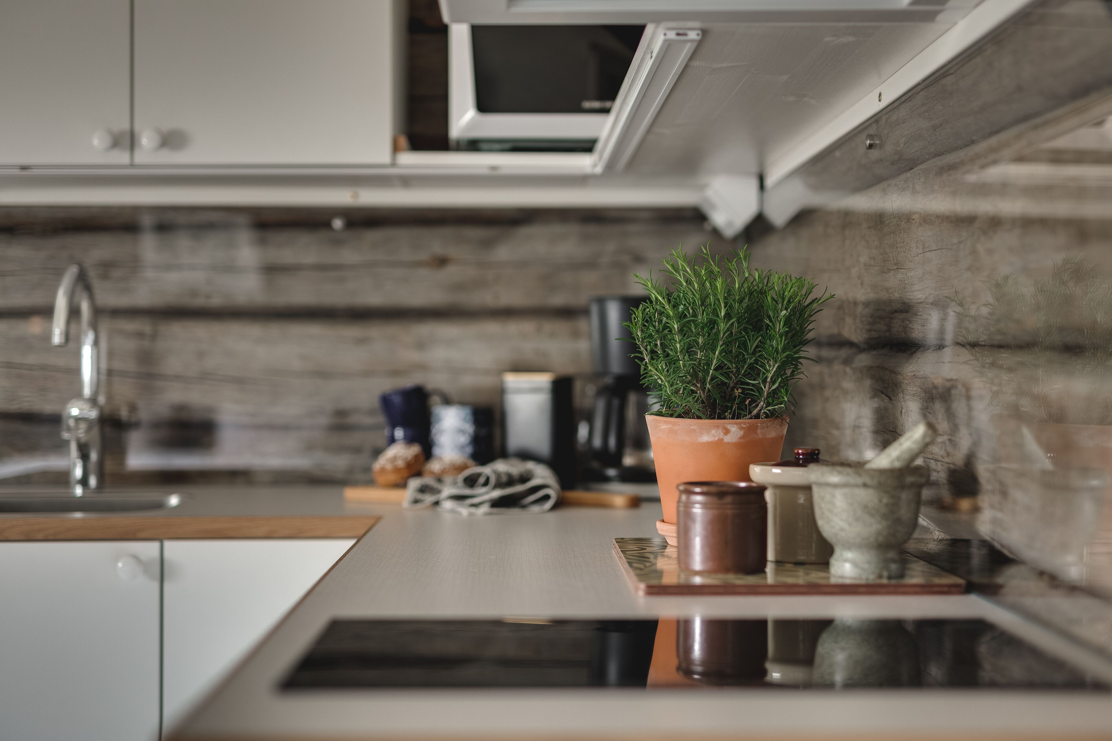 A modern kitchen with a wooden countertop, a sink, a microwave, and a potted plant.