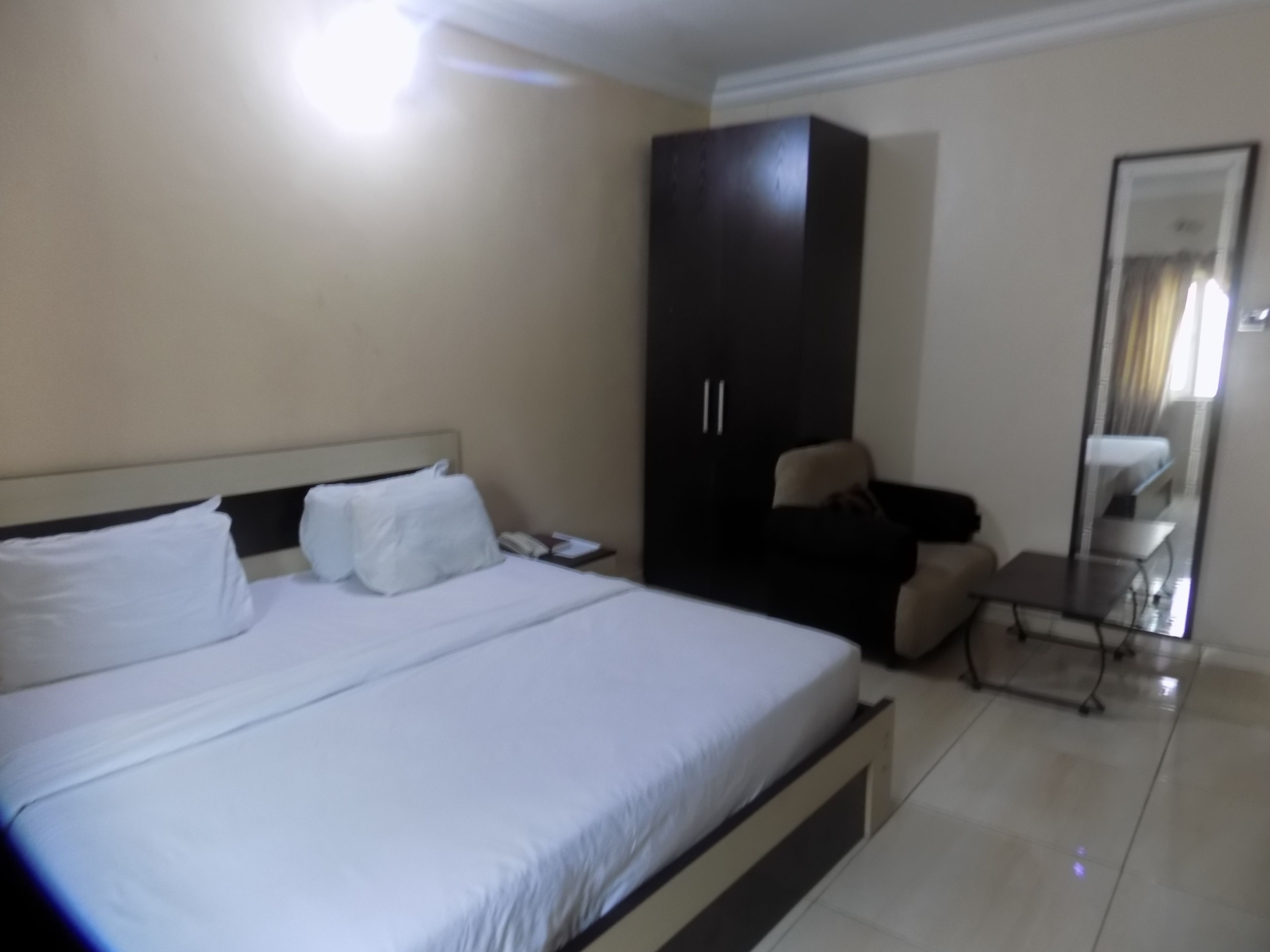 Een hotelkamer met een bed, een kledingkast, een bureau en een spiegel.