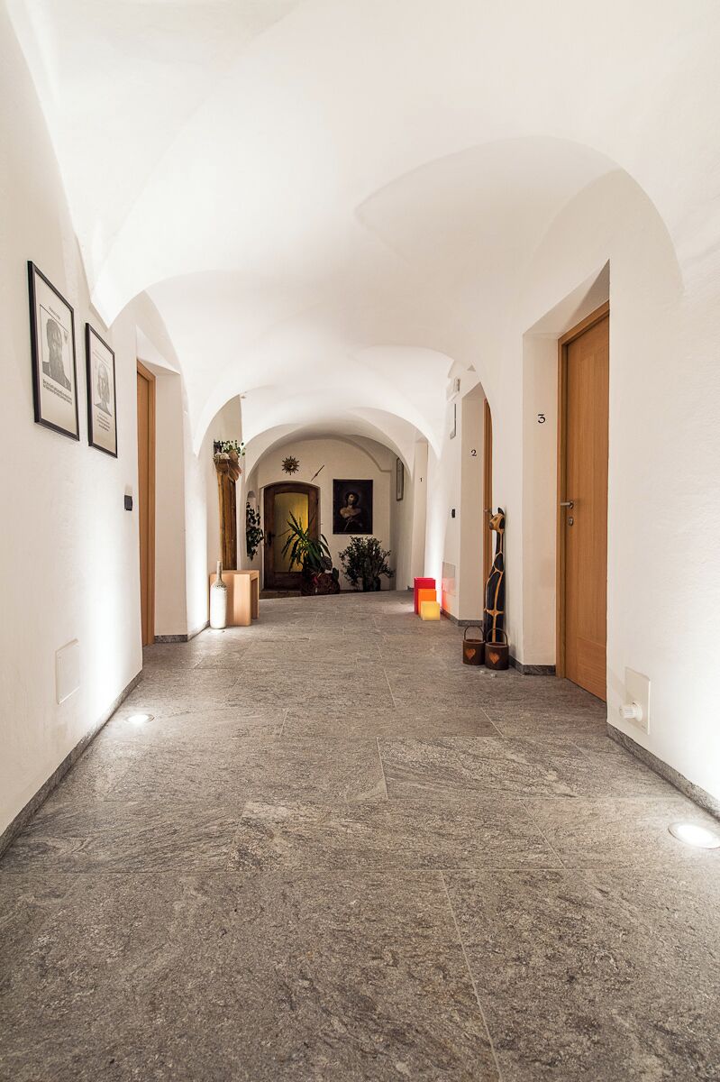 Un pasillo con techos abovedados y suelo de baldosas, que conduce a una puerta con el número 3.
