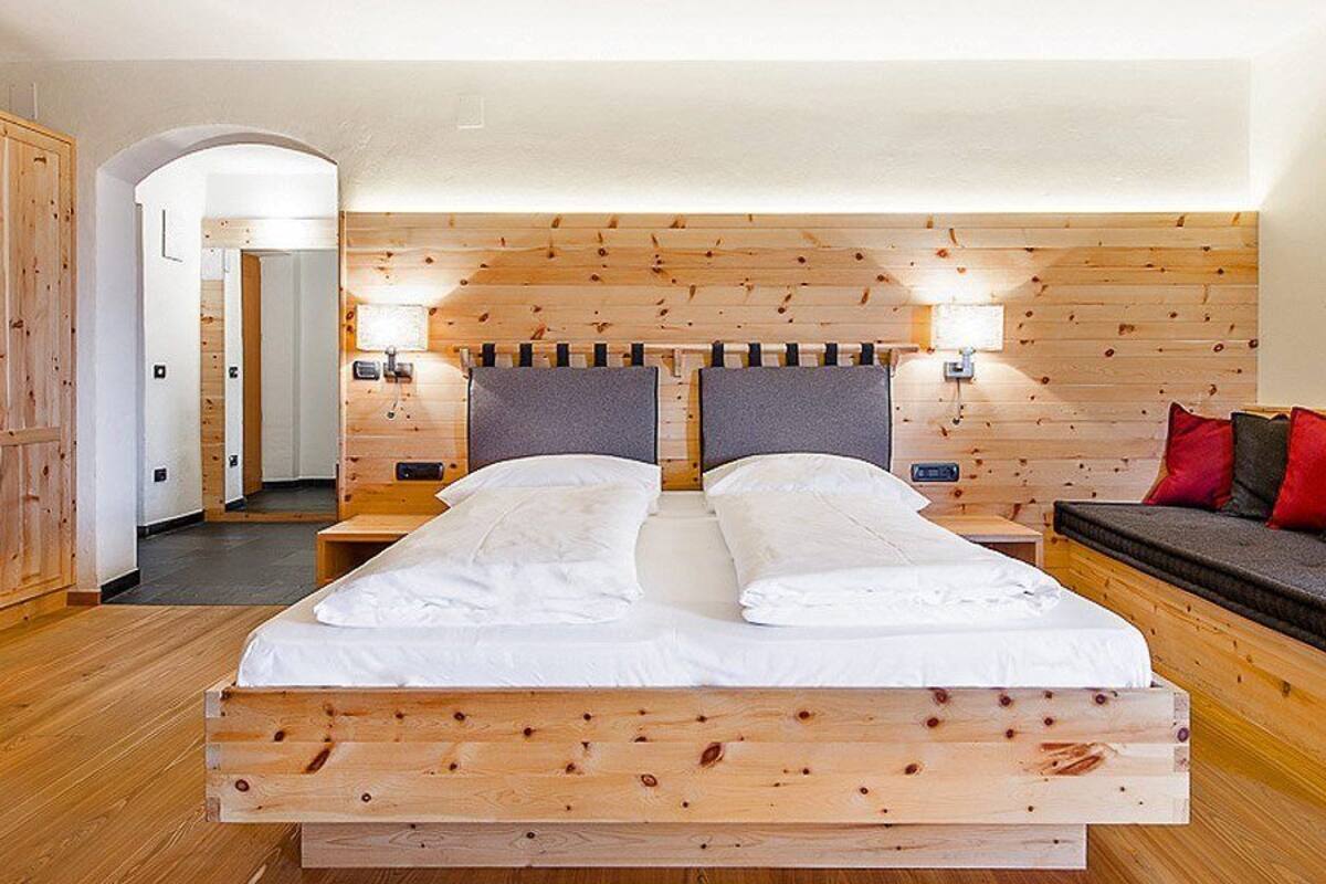 Ein Schlafzimmer mit Holzwänden, einem Bett, einer Bank und einer Wandleuchte.