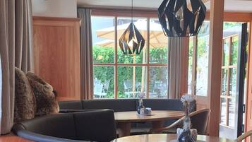 Una sala de estar moderna con un sofá, una mesa de comedor y un amplio ventanal con vistas al verdor.