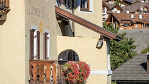 Un bâtiment sur lequel on peut lire l’inscription « Zum Sonne Alsole » et qui possède un balcon orné de fleurs rouges.