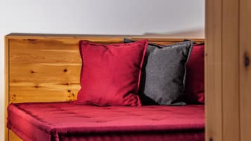 A wooden bed with a red and grey pillow.