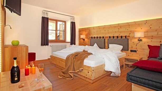 Une chambre confortable avec un lit en bois, des tables de chevet, une télévision et une fenêtre avec des rideaux.