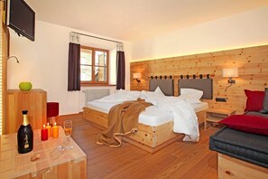 Une chambre confortable avec un lit en bois, des tables de chevet, une télévision et une fenêtre avec des rideaux.