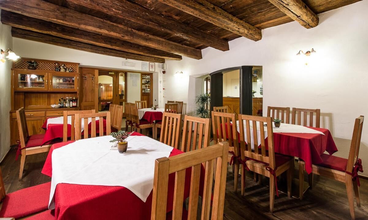 Un comedor con mesas y sillas de madera, manteles rojos y techo de madera rústica.
