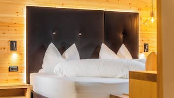 Un lit avec une tête de lit sombre, des oreillers blancs et une table de chevet en bois.