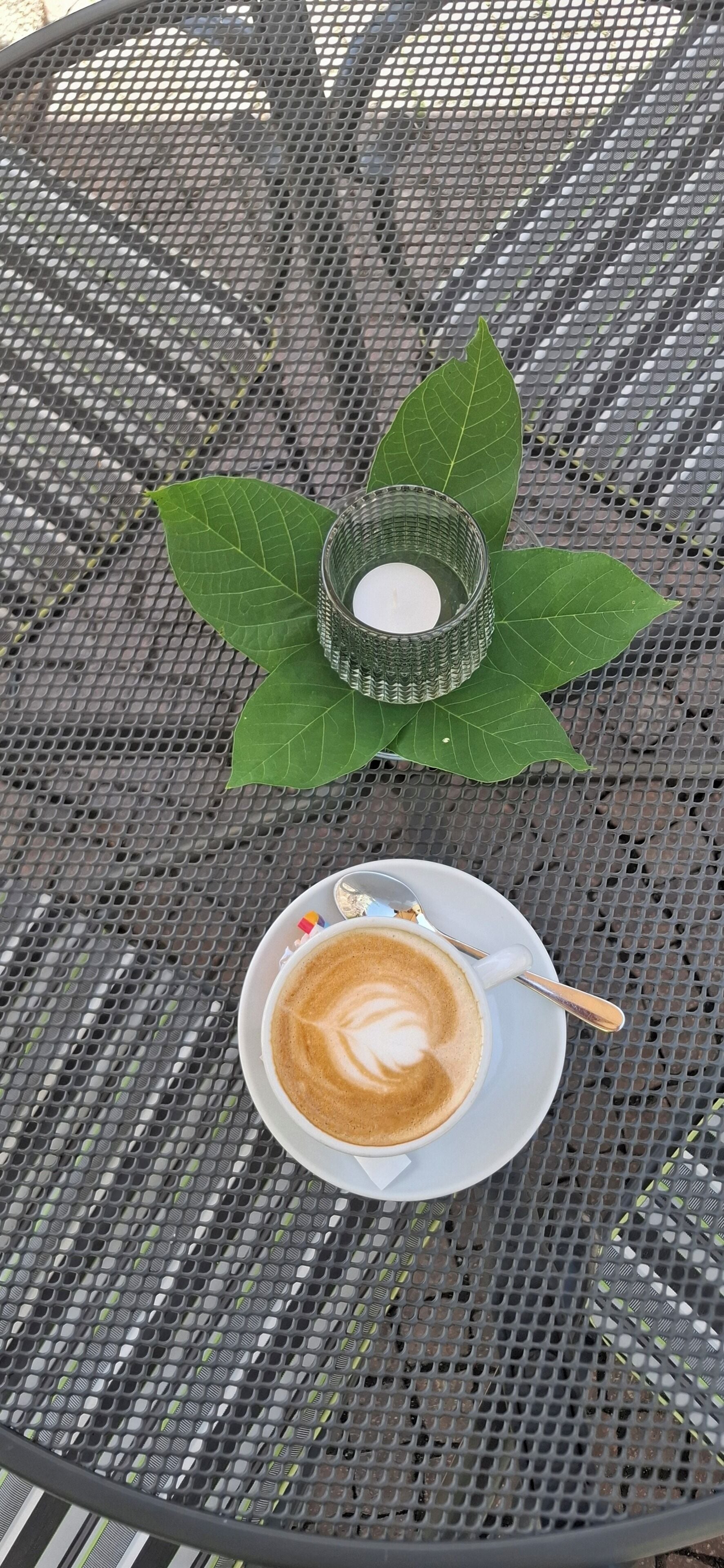 Una mesa de metal con una taza de café y un candelabro encima.