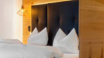Una habitación de hotel con cabecera de madera, ropa de cama blanca y una lámpara colgante.