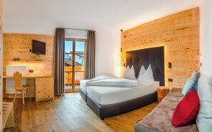 Une chambre d’hôtel équipée d’un lit, d’un bureau, d’une chaise, d’un canapé et d’un téléviseur fixé au mur.