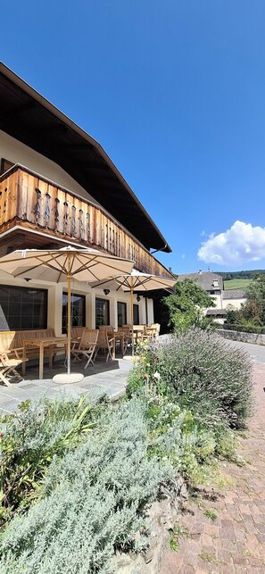 Un bâtiment doté d’un balcon en bois, d’un espace extérieur aménagé pour s’asseoir et d’un jardin.