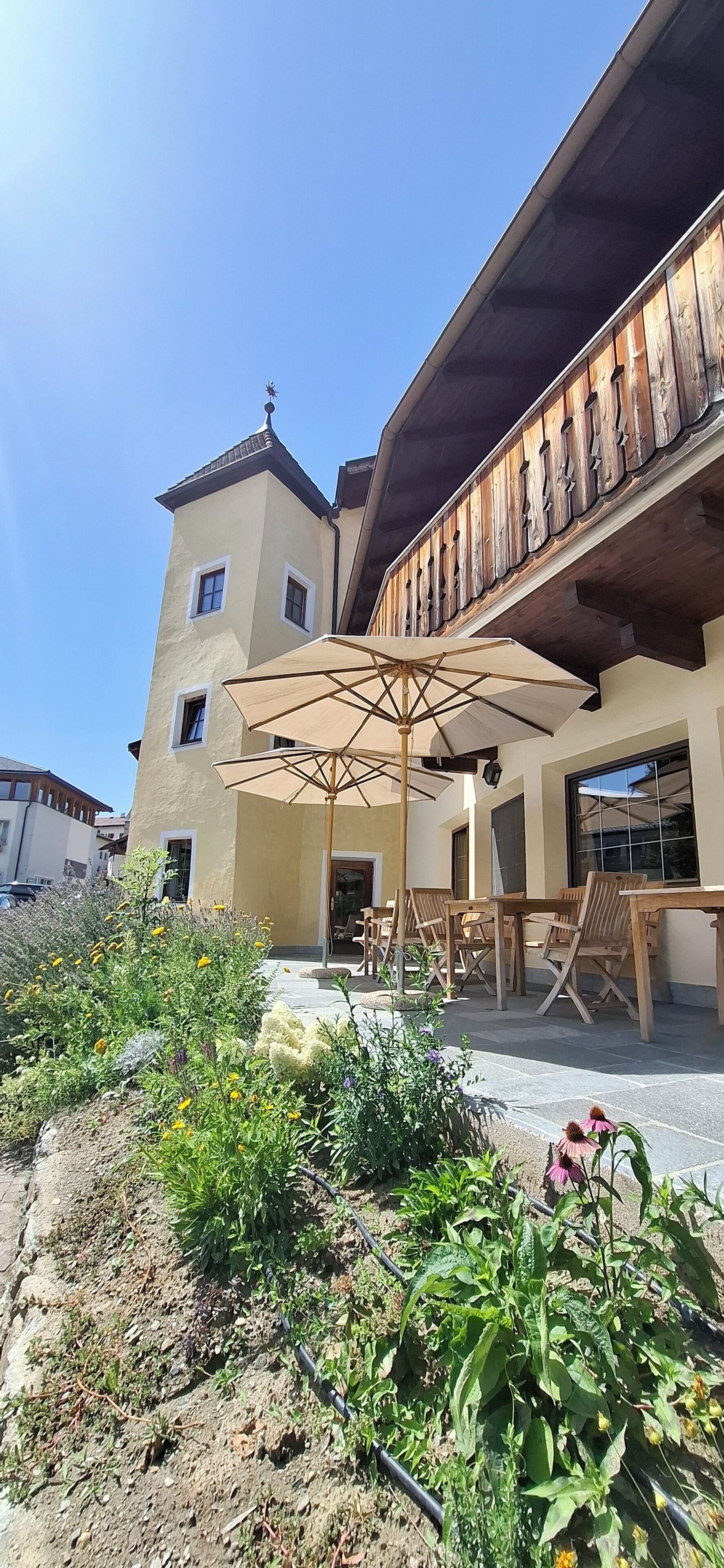 Un bâtiment doté d’un balcon, d’un espace extérieur aménagé pour s’asseoir et d’un jardin.