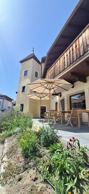 Un bâtiment doté d’un balcon, d’un espace extérieur aménagé pour s’asseoir et d’un jardin.