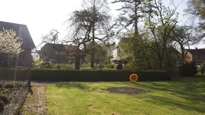 A residential area with a well-maintained lawn, mature trees, and a hedge. - Hotel Cramer (Werlte)