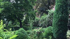 A stone well surrounded by lush greenery and a brick wall. - Hotel Cramer (Werlte)