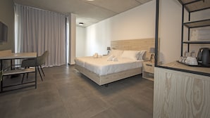 A modern hotel room with a wooden bed, a desk with a chair, a coffee maker, and a TV on the wall. - Mr. Todd Hotel (Sliema)