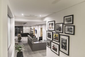 Una moderna zona de recepción con una encimera de mármol, fotografías enmarcadas en la pared y una planta en maceta.