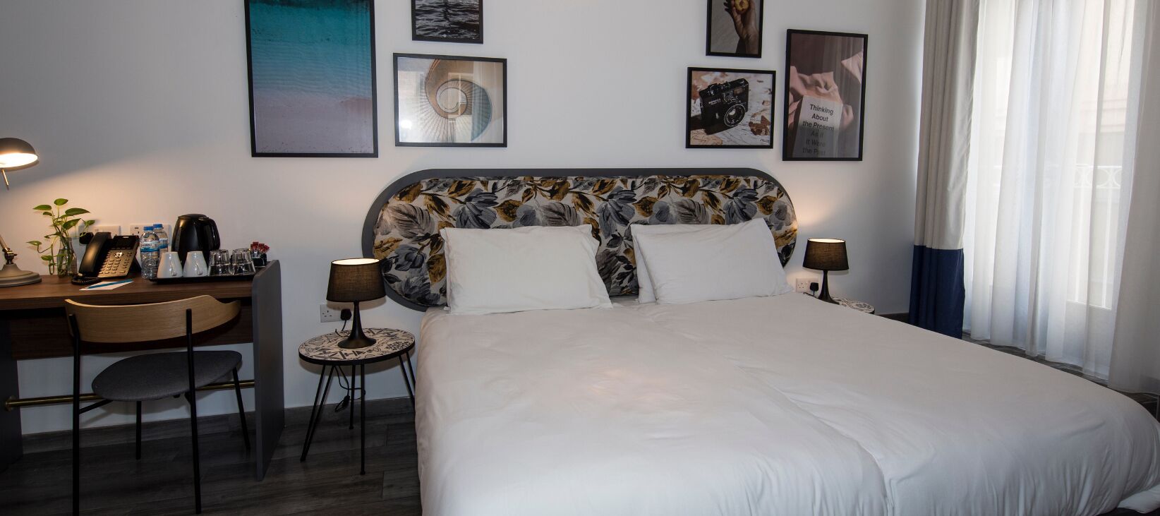 Ein Hotelzimmer mit Bett, Schreibtisch, Stuhl und Lampen.