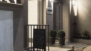 A building with a sign reading "Mr Todd Cafe" and a sign above the door indicating "Hotel > Mr Todd > Cafe". There are potted plants on the steps and a chalkboard with a list of items. - Mr. Todd Hotel (Sliema)