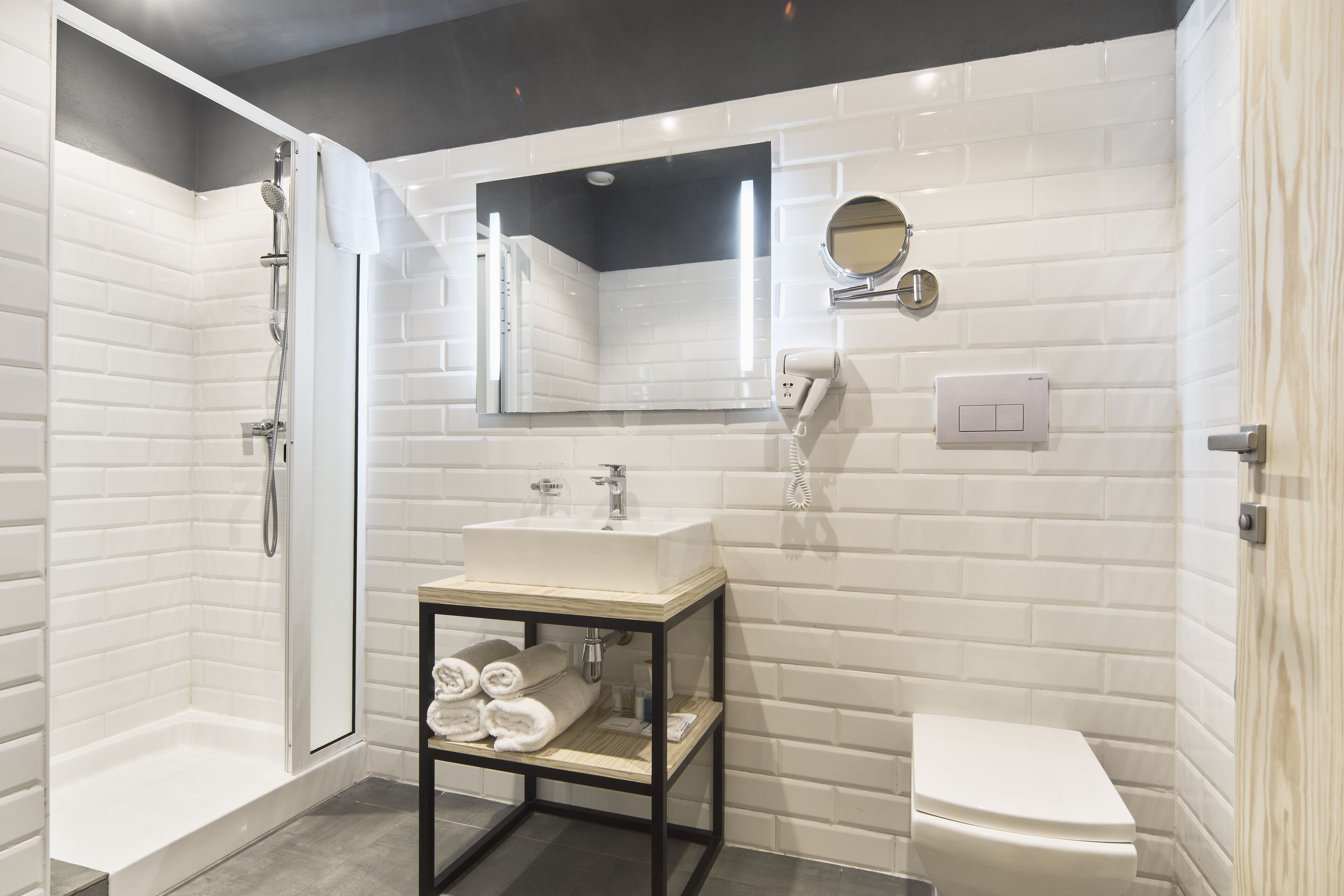 Ein modernes Badezimmer mit einer Duschkabine, einem weißen Waschbecken mit Spiegel darüber und einer Toilette.