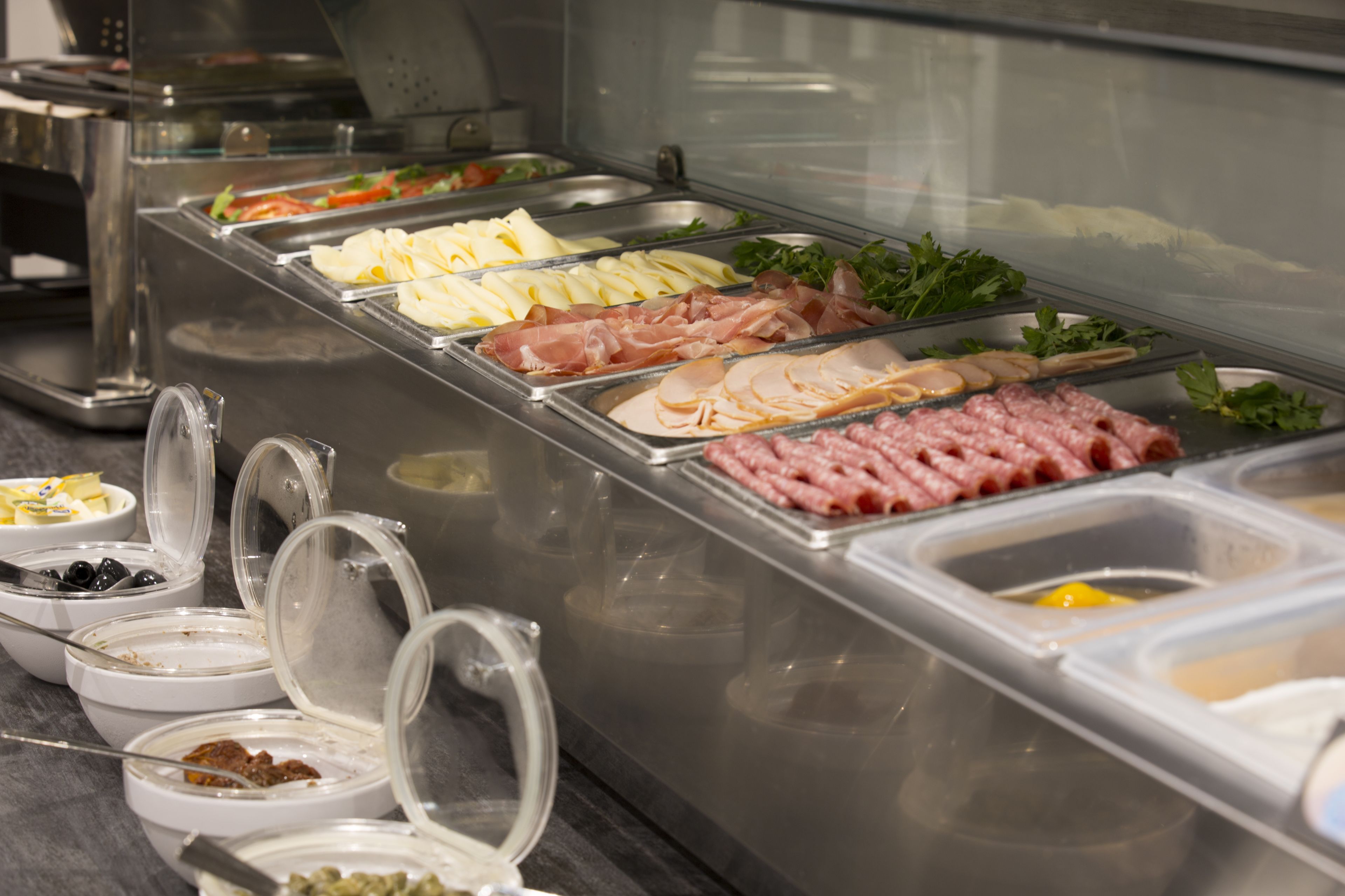 Buffet com diversas opções de comida, incluindo carnes, queijos e vegetais.