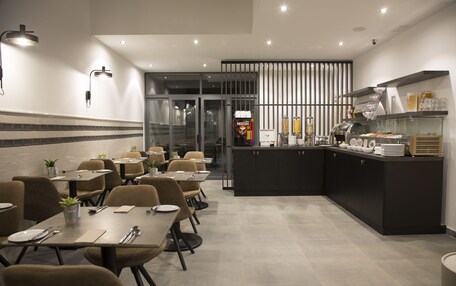 A modern dining area with tables and chairs, a kitchen counter with appliances, and a vending machine.