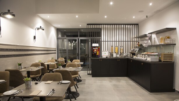 A modern dining area with tables and chairs, a kitchen counter with appliances, and a vending machine. - Mr. Todd Hotel (Sliema)
