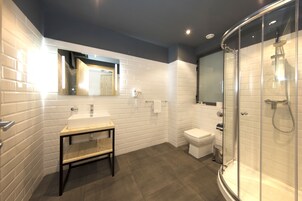 Un bagno moderno con parete rivestita in piastrelle bianche tipo metro, mobile lavabo in legno, box doccia in vetro e water.
