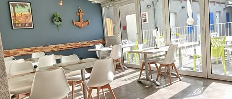 A restaurant with indoor seating, a wooden accent wall, and a view through large glass doors.