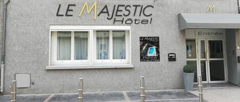 The exterior of Le Majestic Hotel with a sign indicating a swimming pool.