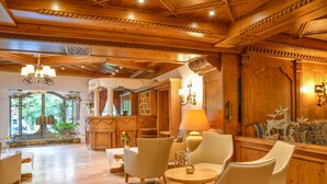 A spacious lobby with wooden paneling, a chandelier, and comfortable seating areas. - Romantik Landhotel Doerr (Bad Laasphe)