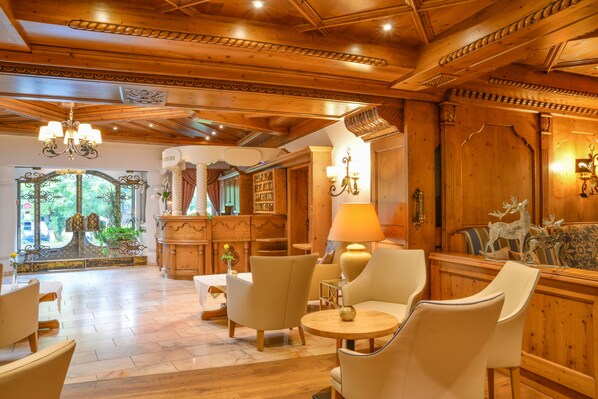 Un vestíbulo amplio con paneles de madera, un candelabro y zonas de estar cómodas.