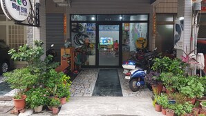 A storefront with a bicycle shop, potted plants, and a parked scooter.