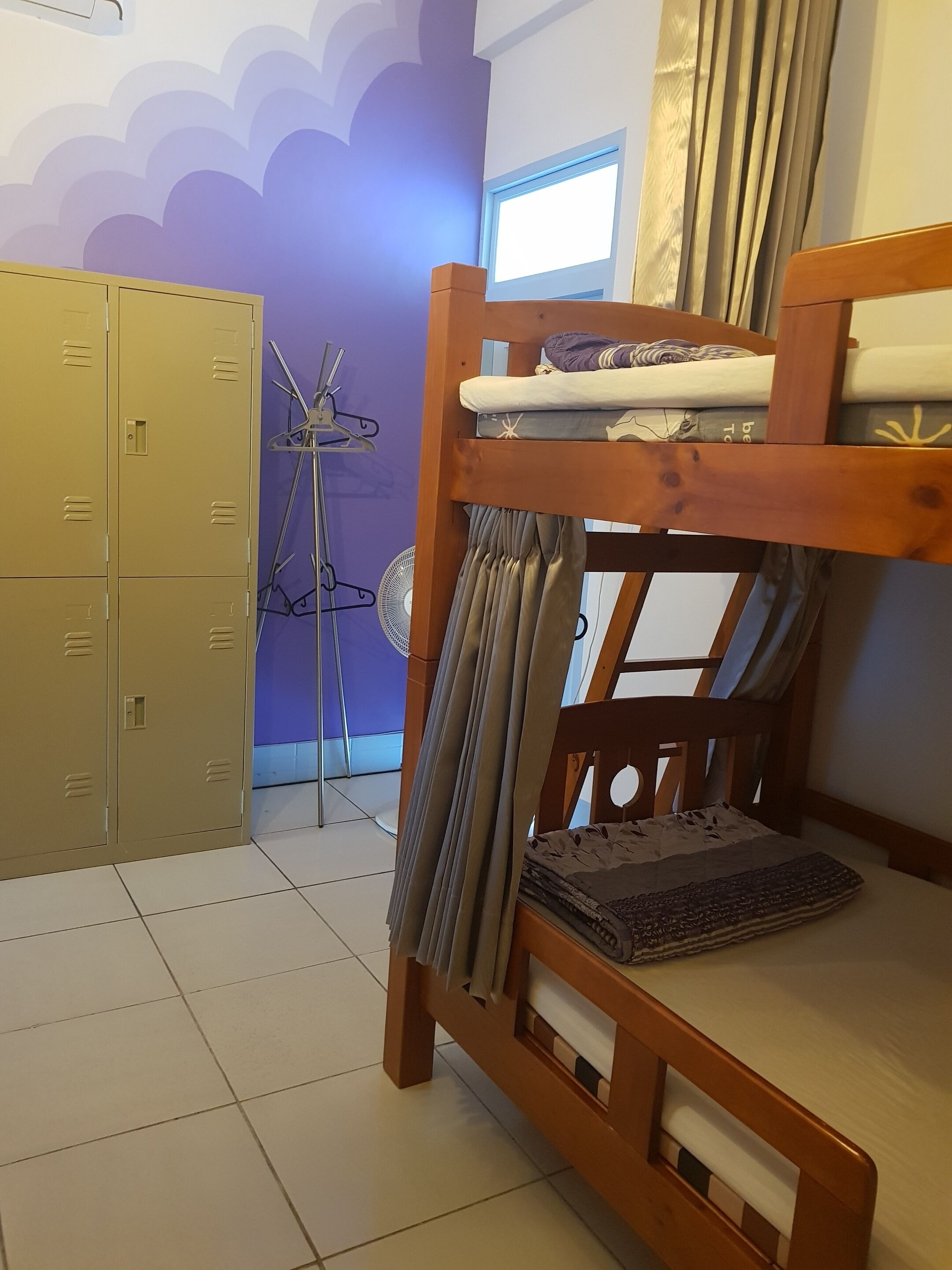 A bunk bed with a window, a fan, and a set of lockers.