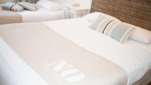Une chambre d’hôtel avec deux lits, chacun étant équipé de draps blancs et d’oreillers à rayures.