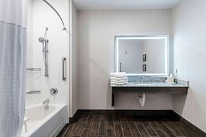 Une salle de bain moderne équipée d’une baignoire, d’une douche et d’un meuble-lavabo avec un miroir.