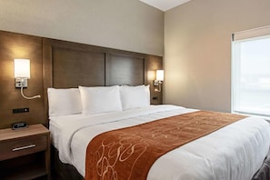 Een hotelkamer met een groot bed, twee nachtkastjes, een wandlamp en een raam.