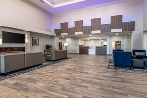 Un hall d’entrée spacieux avec une cheminée, un coin salon et un comptoir d’accueil.