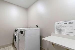 Zona de lavandería para huéspedes con lavadora y secadora, un cartel con instrucciones de uso y una pequeña encimera.