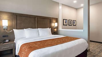 Una habitación de hotel con una cama grande, lámparas de noche, una mesita de noche y un teléfono en la pared.
